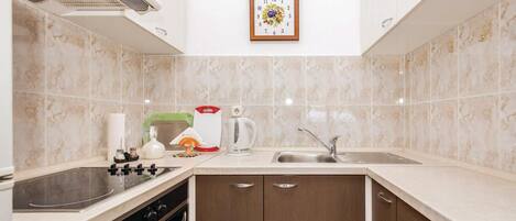 A modern kitchen with a built-in oven, a stovetop, a sink, and wooden cabinets.