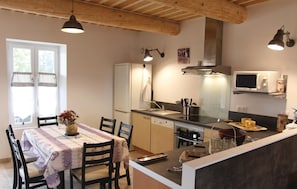 Cocina compacta con zona de comedor, que incluye un refrigerador, microondas, pileta y una pequeña isla con un microondas encima.