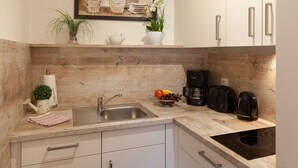 A modern kitchen with a wooden countertop, stainless steel sink, and black appliances.