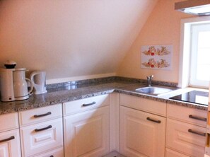 A kitchen with white cabinets, a granite countertop, a sink, and a coffee maker. - Vacation apartment Spieker 2nd floor - Waldseiter Hof (Bad Bentheim)