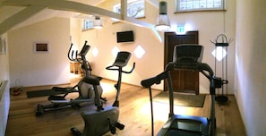 A gym with exercise equipment, wooden flooring, and a door in the background.