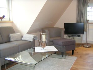 A living room with a sofa, a glass coffee table, a television, and a floor lamp.