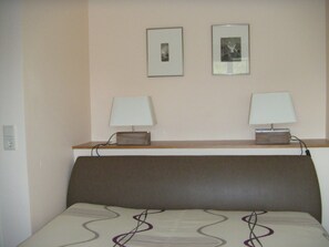 A hotel room with a bed, two bedside lamps, and two framed pictures on the wall. - Vacation apartment Spieker 2nd floor - Waldseiter Hof (Bad Bentheim)