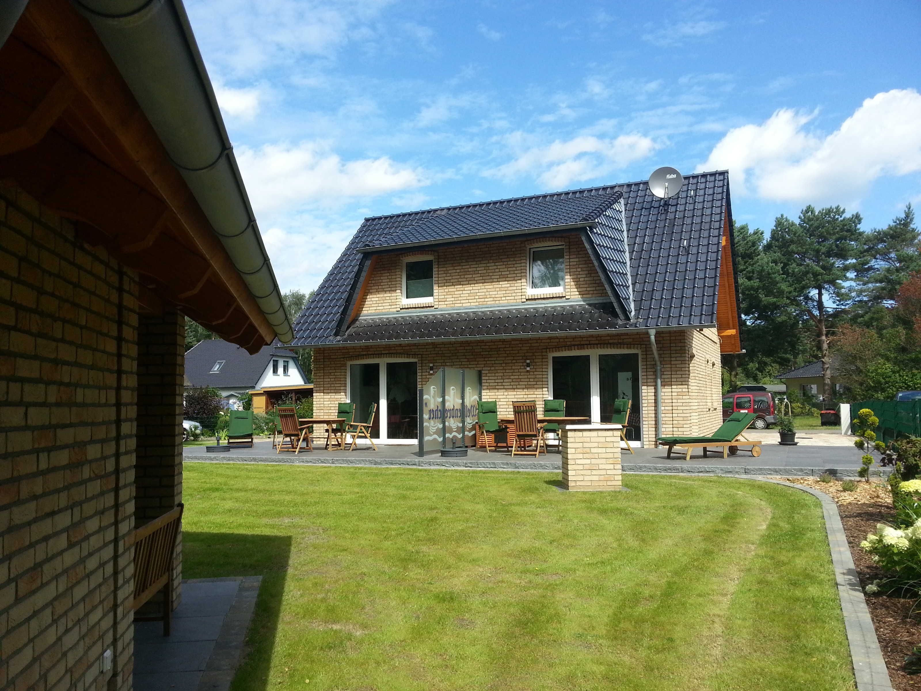 A two-story house with a brick facade, a tiled roof, and a front porch with outdoor furniture.