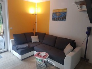 Uma sala de estar moderna com um sofá seccional, uma mesa redonda pequena e um quadro na parede.