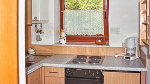A compact kitchen with a built-in stove, a coffee maker, and a window with a view of greenery. - 1 bedroom awesome home in Prümzurlay (Prümzurlay)