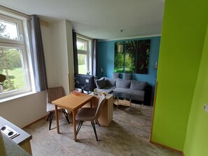 A modern living room with a dining area, a sofa, and a TV.