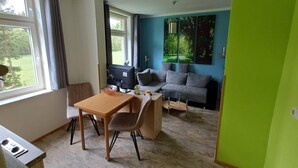 A modern living room with a dining area, a sofa, and a TV.