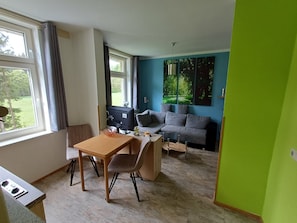 Una sala de estar moderna con comedor, un sofá y un televisor.