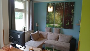 A modern living room with a sectional sofa, a glass coffee table, and a flat-screen TV.
