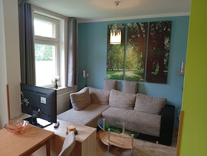 Una sala moderna con un sofá modular, una mesa de centro de vidrio y un televisor de pantalla plana.