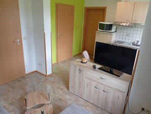 A compact kitchen with a microwave, a television, and a small cabinet.