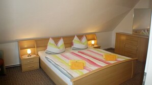 A bedroom with a bed, two bedside tables, a nightstand, a dresser, and a mirror. - App 2 (40m²) - Rügen-Fewo 267 (Mönchgut)