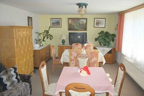 A dining area with a checkered tablecloth, wooden chairs, a television, and framed pictures on the wall. - App 2 (40m²) - Rügen-Fewo 267 (Mönchgut)
