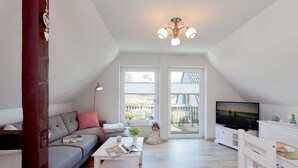 A modern living room with a grey sofa, white coffee table, and a television.