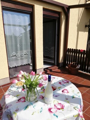 A patio with a table set for a meal, a bottle of Tropicol, and a vase with flowers. - *** FW 3 on the ground floor with large terrace - *** Ferienwohnungen Wiesenblick (Trassenheide)