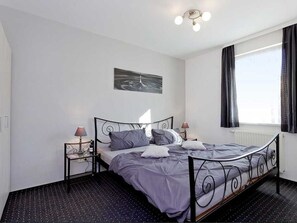 A bedroom with a bed, two bedside tables, a wall-mounted artwork, and a window with curtains. - *** FW 3 on the ground floor with large terrace - *** Ferienwohnungen Wiesenblick (Trassenheide)