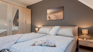 A bedroom with a bed, bedside tables, a wardrobe, and a painting on the wall.