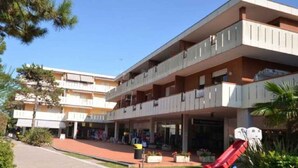 Et hotel med flere etager, altaner, en rød rutsjebane og udendørs siddepladser.