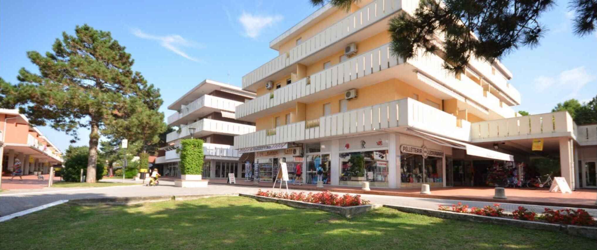 A multi-story hotel with balconies, a central courtyard, and storefronts on the ground floor.