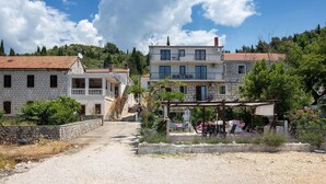 A two-story building with a stone facade, a balcony on the upper floor, and a gravel driveway leading to the entrance. - 2 bedroom gorgeous apartment in Blace (Blace)