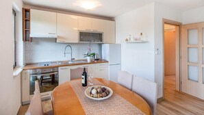 A modern kitchen with white cabinets, a stainless steel sink, and a dining area with a round table and chairs. - 2 bedroom gorgeous apartment in Blace (Blace)