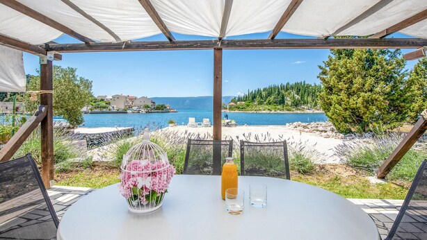 A covered outdoor seating area with a table, a bottle, and glasses. - 2 bedroom gorgeous apartment in Blace (Blace)