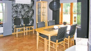 A dining area with a wooden table and chairs, a patterned wall, and a window with a view of greenery.
