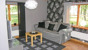 A living room with a grey sofa, black cushions, a small wooden table, and a patterned rug.