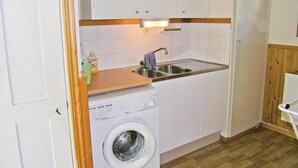 A compact kitchen with a washing machine, a sink, and wooden cabinets.