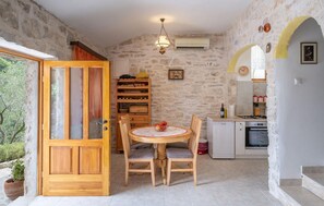 Eine rustikale Küche mit Steinwand, Holzausbau, einem runden Tisch mit Stühlen und einer kleinen Essecke.