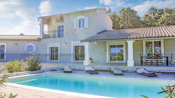Une maison à deux étages avec une piscine, un espace salon extérieur et un balcon.