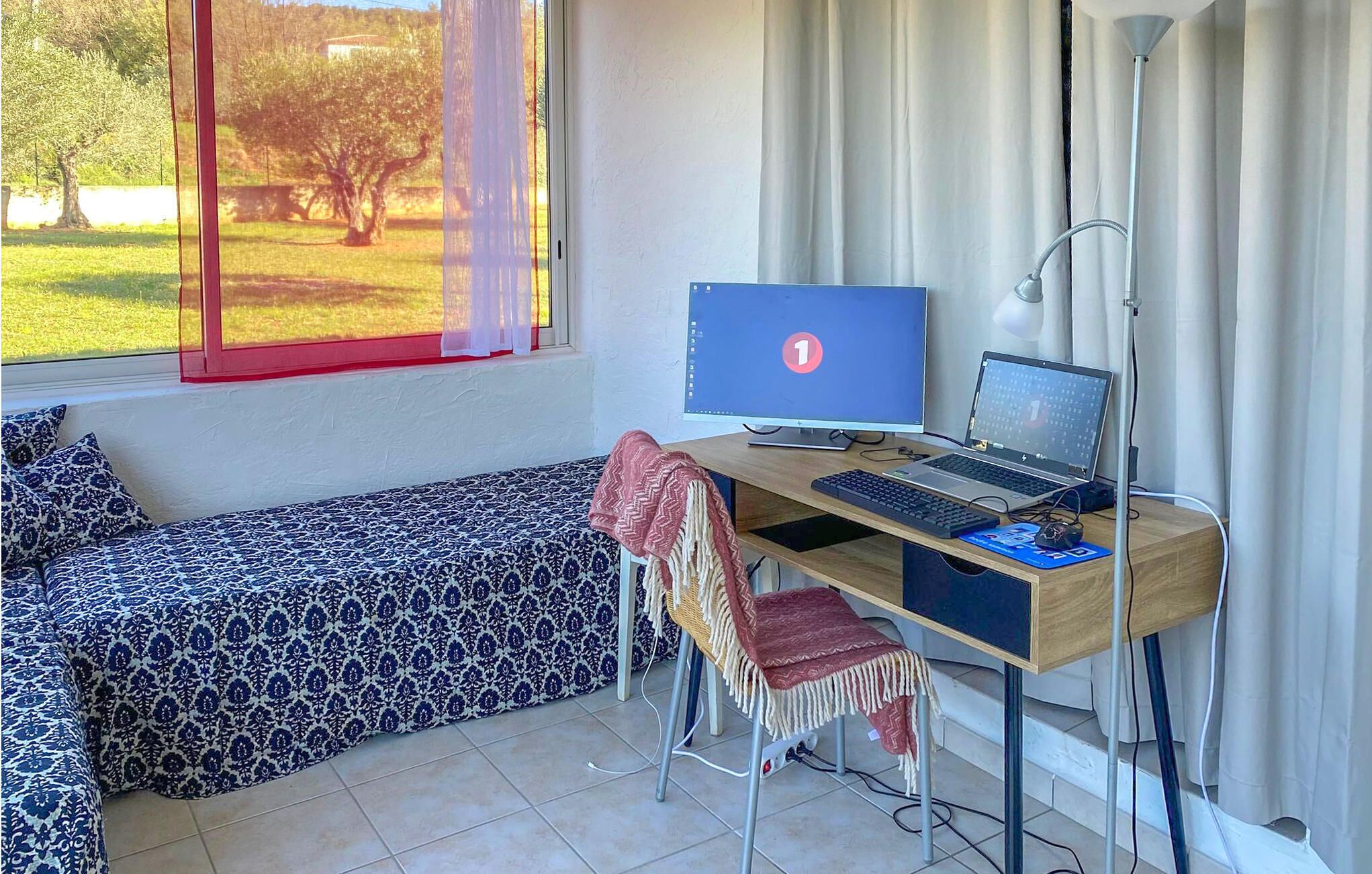 Une chambre avec un lit, un bureau équipé d’un ordinateur et une vue sur un parc par la fenêtre.