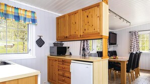 Une cuisine dotée de meubles en bois, d’un four à micro-ondes, d’un réfrigérateur et d’un coin repas avec une table et des chaises.