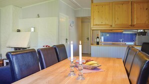 Un coin repas avec une table en bois, des chaises en cuir noir et un chandelier servant de centre de table.
