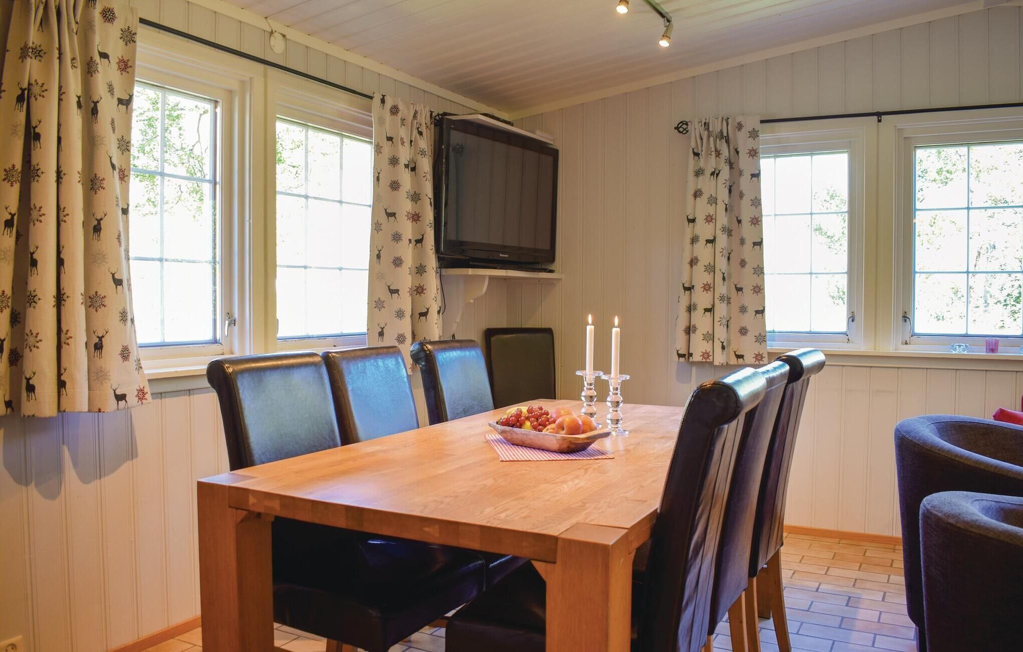 A dining area with a wooden table, chairs, and a TV mounted on the wall.