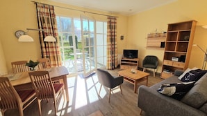 En stue med spiseområde, sofa, fjernsyn og bogreol.