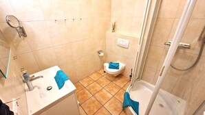 Et lille badeværelse med vask, toilet og brusebad.