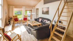 A spacious living room with a black leather sofa, wooden furniture, and a wooden staircase. - Amazing home in Glesborg with sauna (Glesborg)