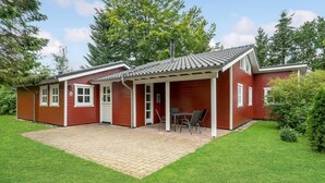 A red single-story house with a covered patio, a chimney, and a small garden. - Amazing home in Glesborg with sauna (Glesborg)