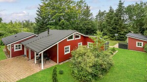 A red house with a tiled roof, a brick driveway, and a well-maintained lawn. - Amazing home in Glesborg with sauna (Glesborg)