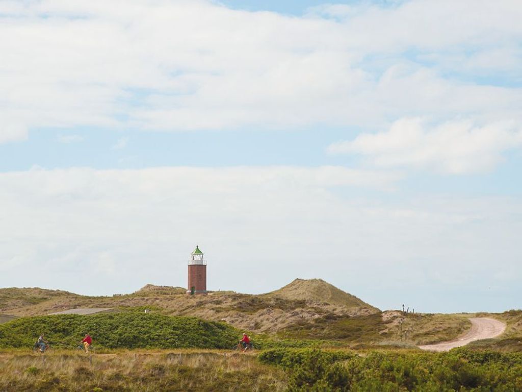 A lighthouse on a hill with a dirt path leading up to it.