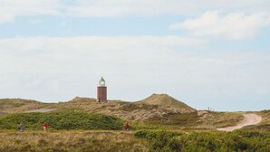 Un phare perché sur une colline, avec un sentier de terre qui y mène.