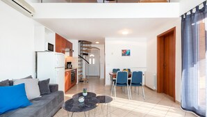 Un apartamento moderno con sala de estar, comedor, cocina y una escalera que conduce a un piso superior.