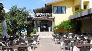 An outdoor dining area with tables and chairs arranged in rows, leading to a building with a sign that reads "Ristorante Le Terrazze Pizzeria". - Holiday apartment with pool and air conditioning (Peschiera del Garda)