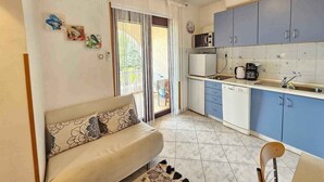 Un espacio habitable funcional con sofá, kitchenette y zona de comedor.