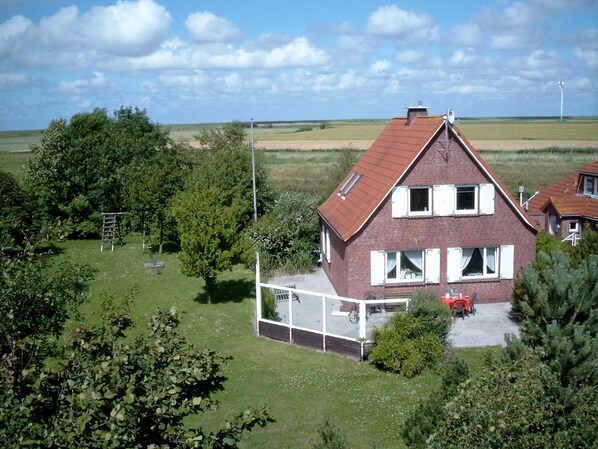 Une maison à deux étages avec un toit en pente, une cour arrière clôturée et une antenne parabolique bien visible.
