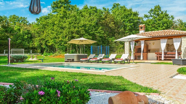 Ein Swimmingpool mit Liegestühlen, einer Grillgelegenheit und einem Blumen-Garten.