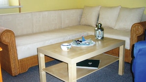 Ett vardagsrum med en beige soffa, ett soffbord i trä, en liten dekorativ båt och en lykta.