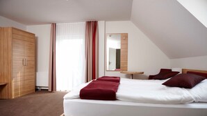 Una habitación de hotel con cama, armario, espejo y ventana con cortinas.